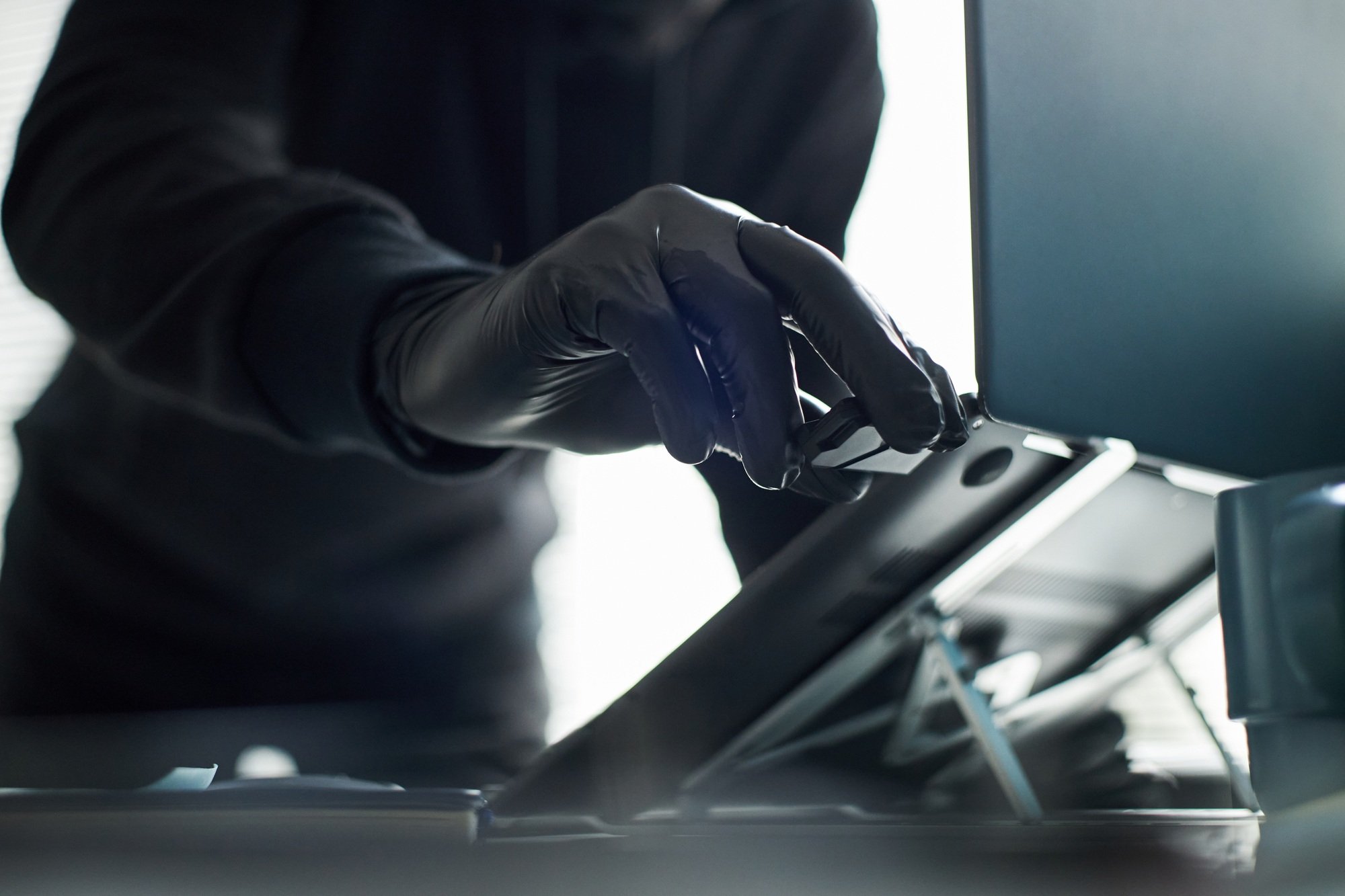 Unrecognizable Man in Black Gloves Breaking in and Accessing Laptop in Office